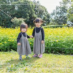 お花畑をバックに姉妹で手をつないで。お揃いの衣装がとっても可愛いです。